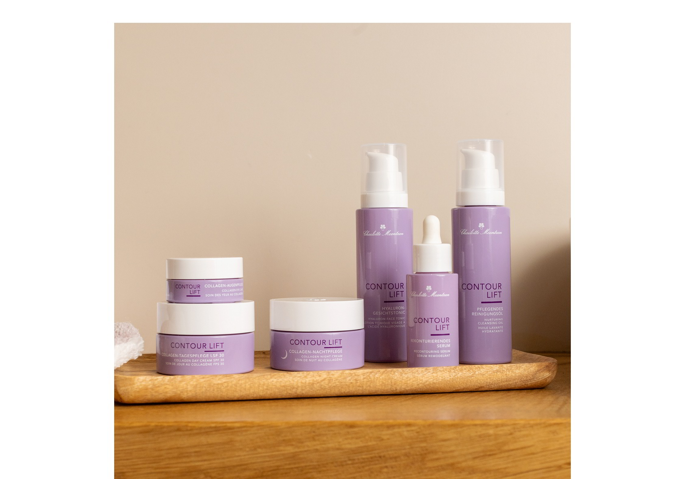 Die komplette Contour Lift Produktgruppe steht in einem Badezimmerauf einem Holztablett.