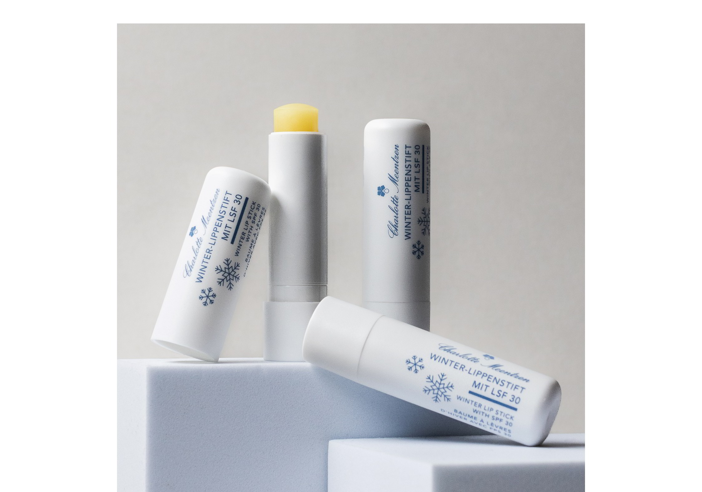 3 Lippenstifte auf Podesten angeordnet. Einer davon ist geöffnet.