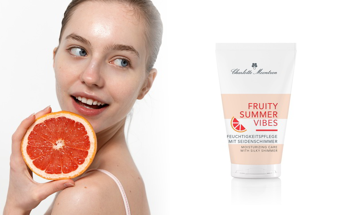 Junge Frau mit Grapefruit ind er Hand, schaut zu Produtktube Freuity Summer Vibes Feuchtigkeitspflege