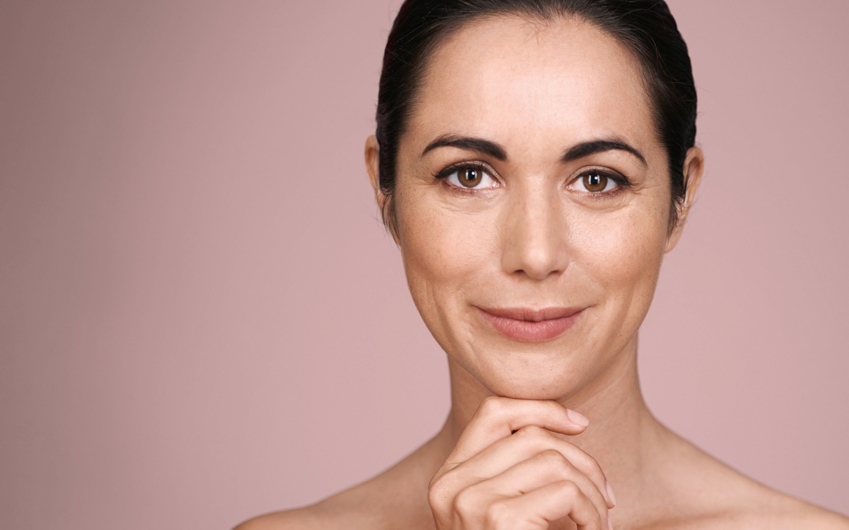 Eine Frau mit einem sanften Lächeln vor einem rosa Hintergrund.